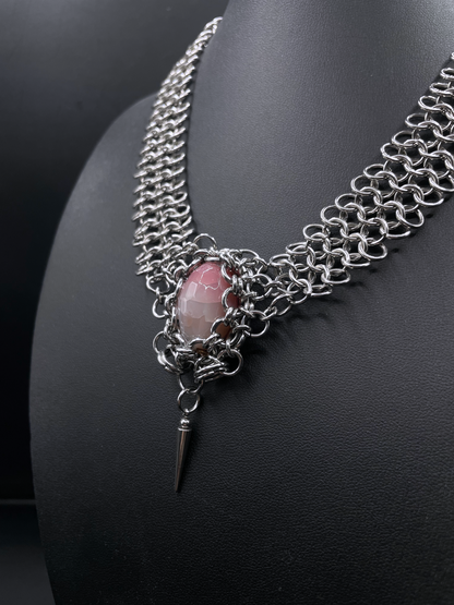 Chainmail necklace with a pink stone and spike pendant on a black background